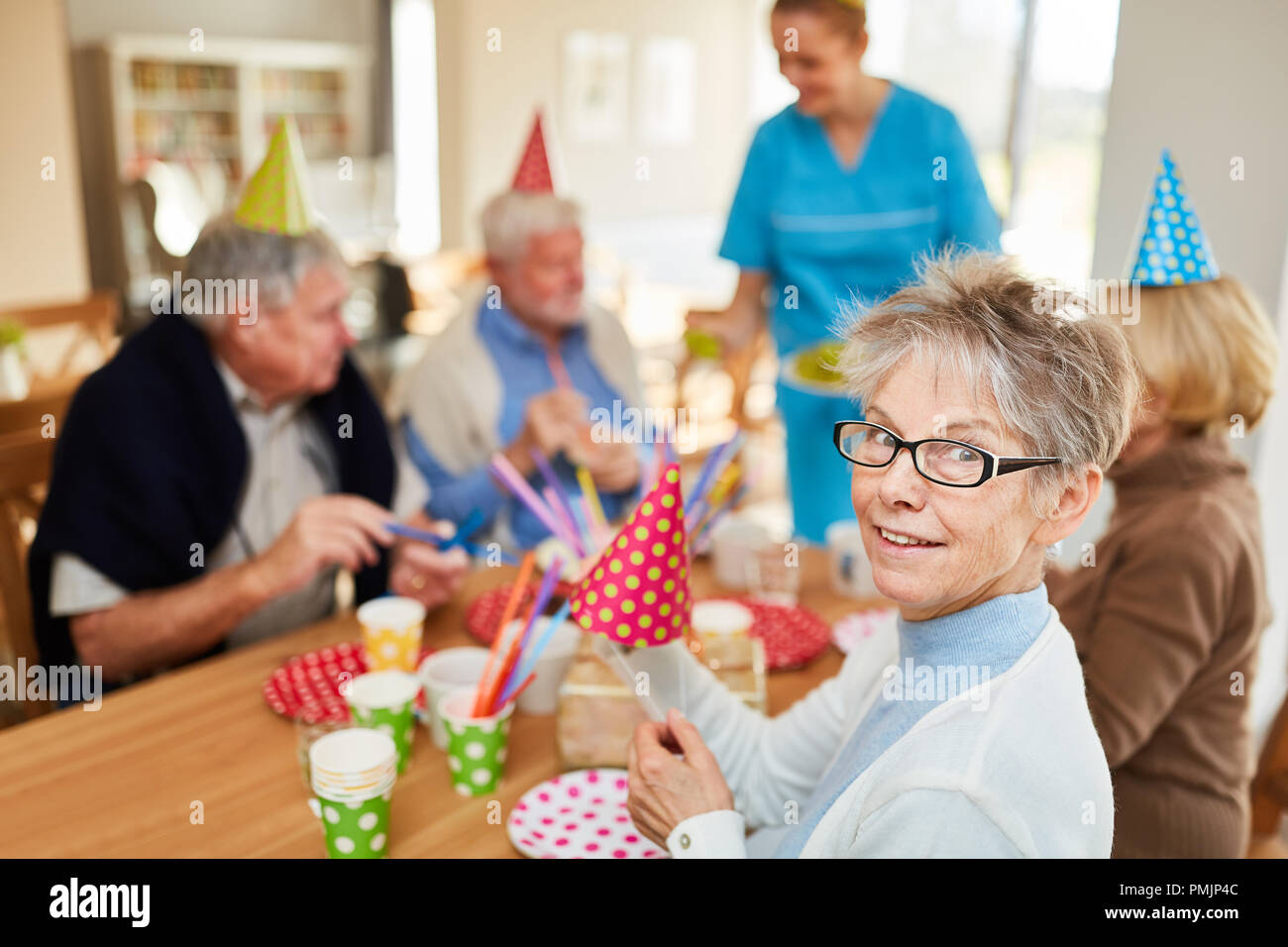 Happy seniors a una festa di compleanno in casa di riposo al tavolo da caffè Foto Stock