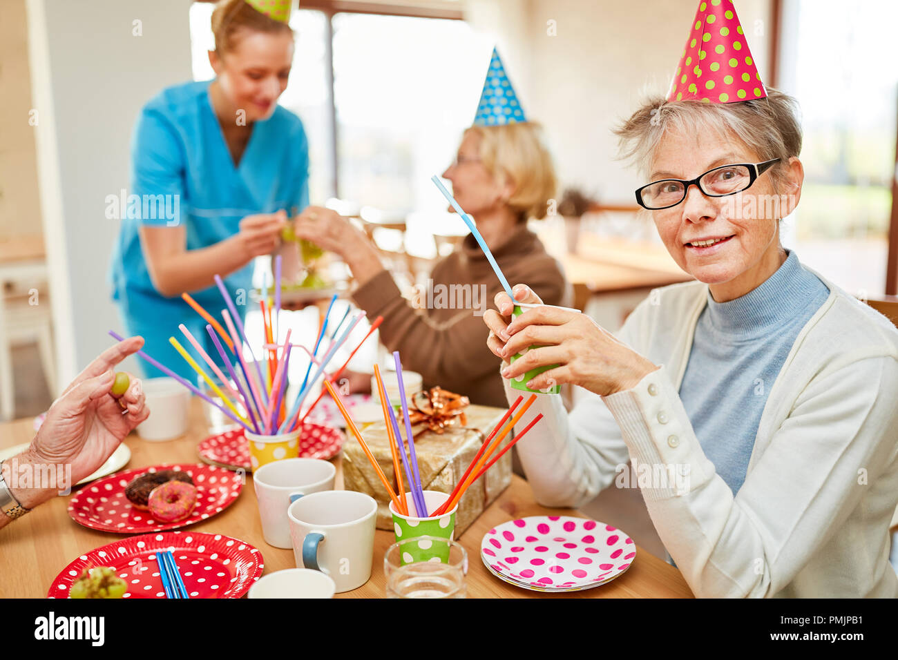 Gli anziani siedono insieme e bere un caffè a una festa di compleanno alla casa di riposo Foto Stock