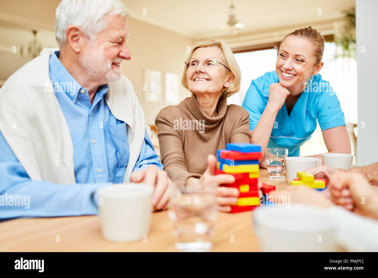 Assistenza infermieristica si prende cura di demented i cittadini anziani a giocare con i blocchi di costruzione Foto Stock