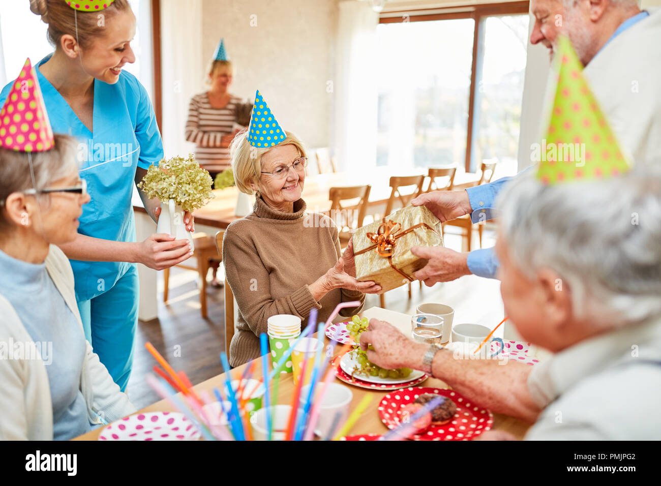 Senior donna è felice circa un dono alla sua festa di compleanno presso il tavolo del caffè Foto Stock