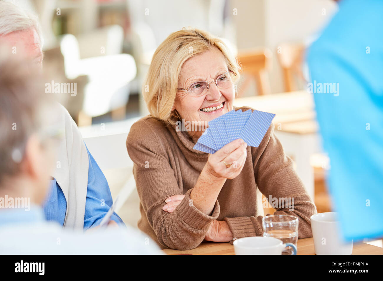 Senior pensionati donna svolge schede insieme con gli amici in una casa di riposo Foto Stock