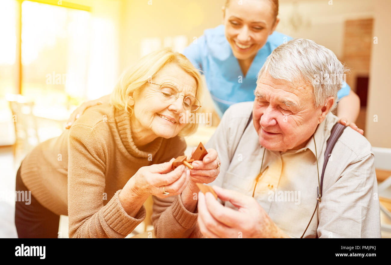Due anziani giocare insieme un plug-in gioco nella casa di cura con il caregiver Foto Stock