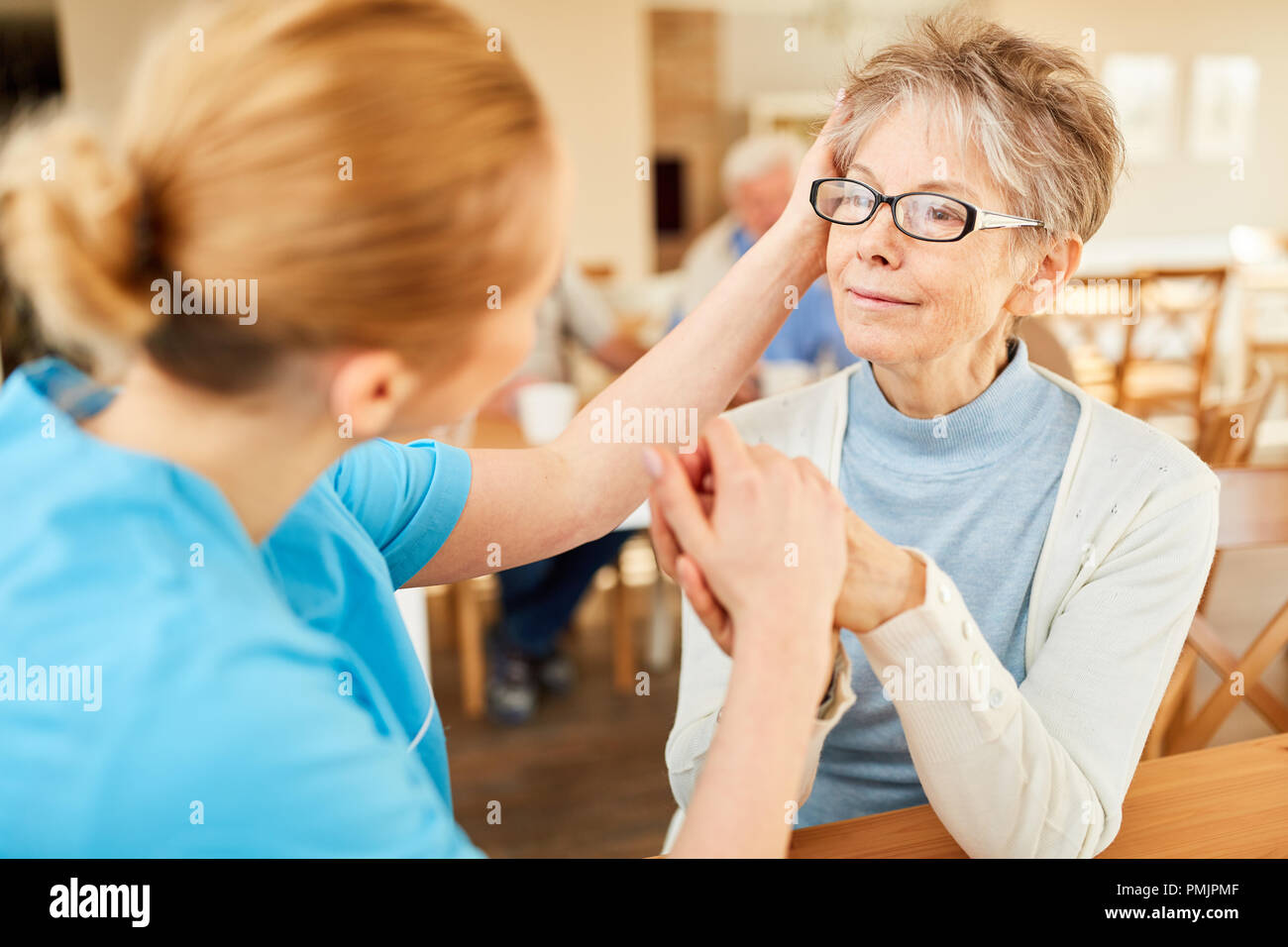 Cura il caregiver comfort donna anziana con demenza o depressione in casa di riposo Foto Stock