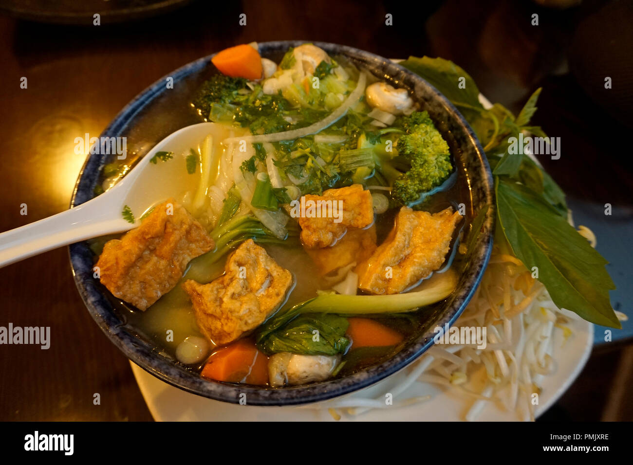 Close-up di una ciotola di vietnamiti vegetariane e vegane pho con tofu, Mung bean germogli e di foglie di basilico fresco sul lato Foto Stock