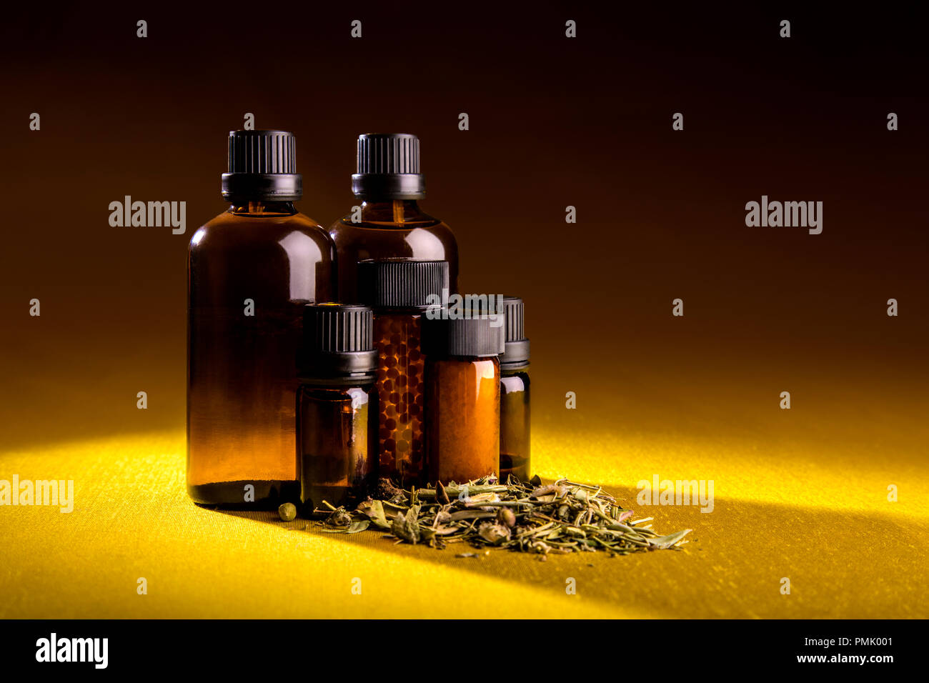 Studio shot di bottiglie di vetro delle terapie omeopatiche tinture, pillole e erbe aromatiche sparse Foto Stock