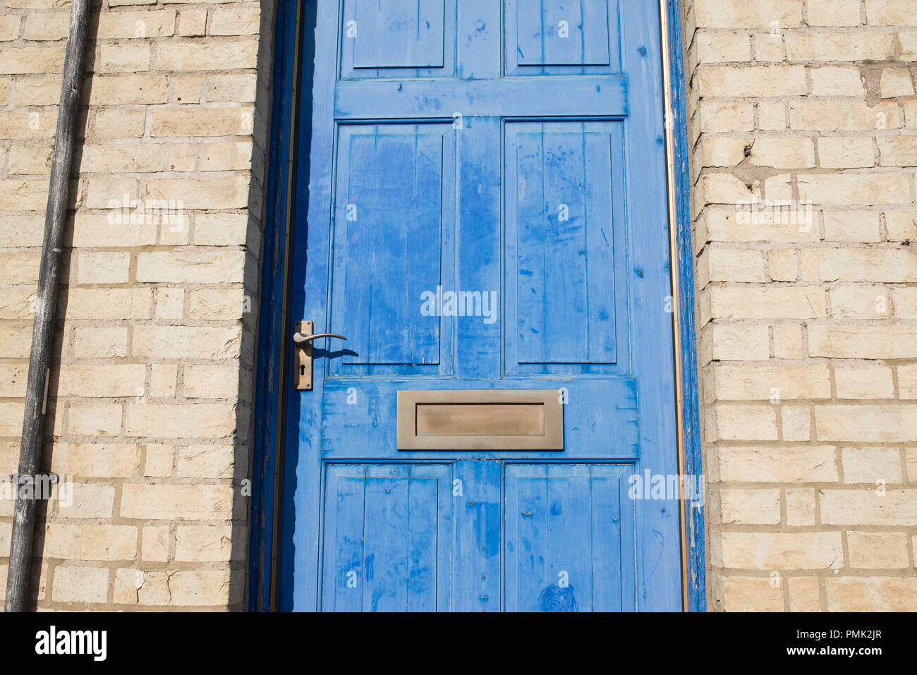 Porta in ottone letterbox su un blu vintage porta anteriore di un giallo un muro di mattoni Foto Stock