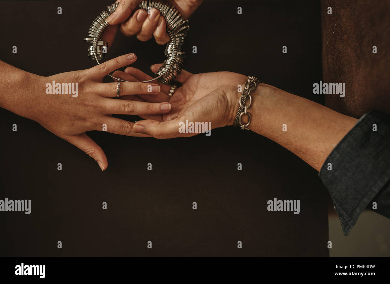 Primo piano della donna anello di controllo dimensioni della mano femminile in gioielleria. Donna cerca un anello indicatore dimensione sul suo client dell anello dito. Foto Stock