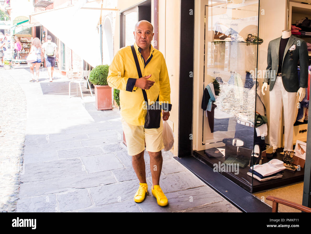 Ritratto di uomo che indossa abiti di colore giallo, in piedi accanto al negozio di abbigliamento, Portafina, Genova, Italia, Europa Foto Stock