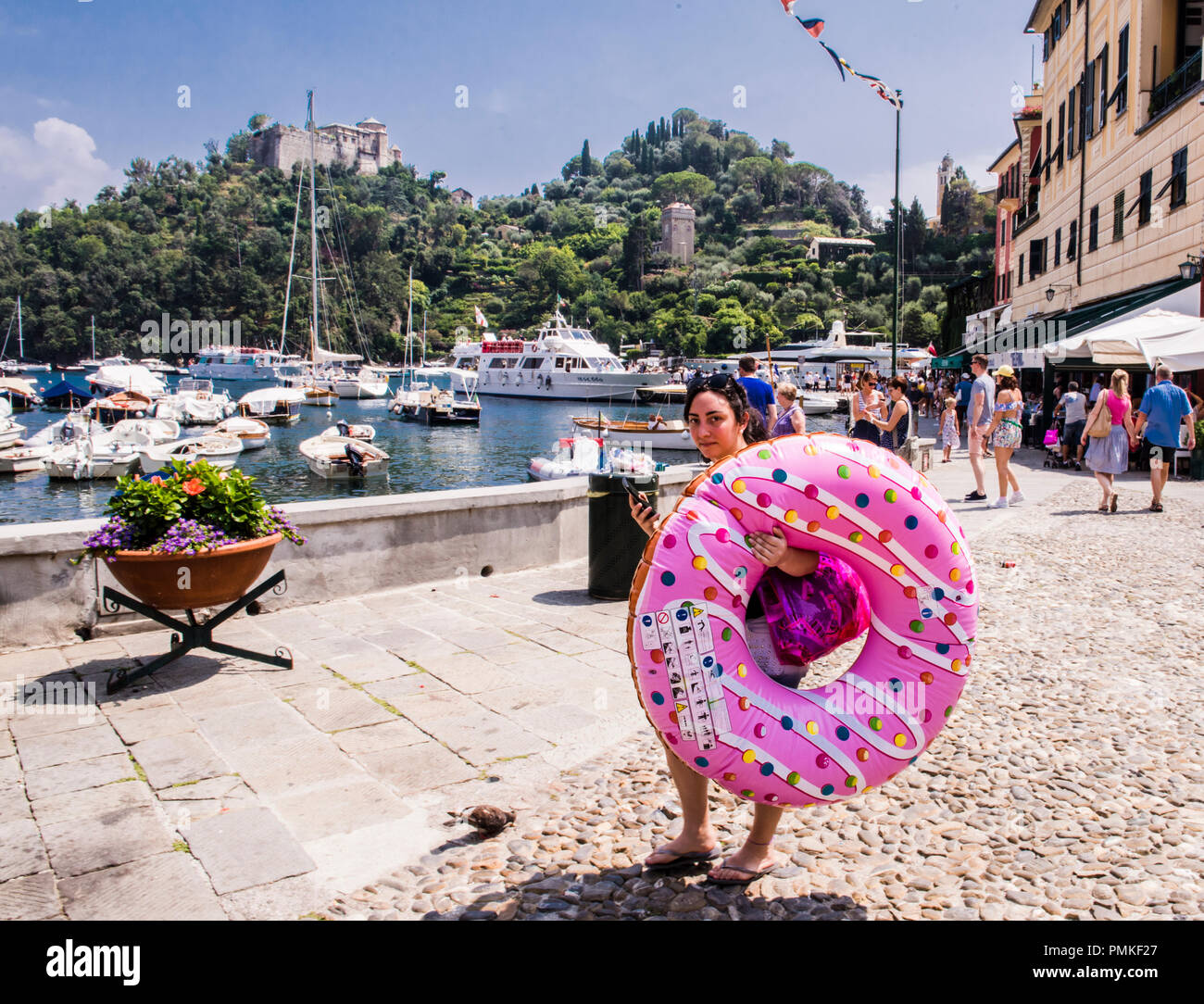 Giovane donna che porta a ciambella gonfiabile a forma di anello, a piedi dal porto, Portofino, Genova, Italia, Europa Foto Stock