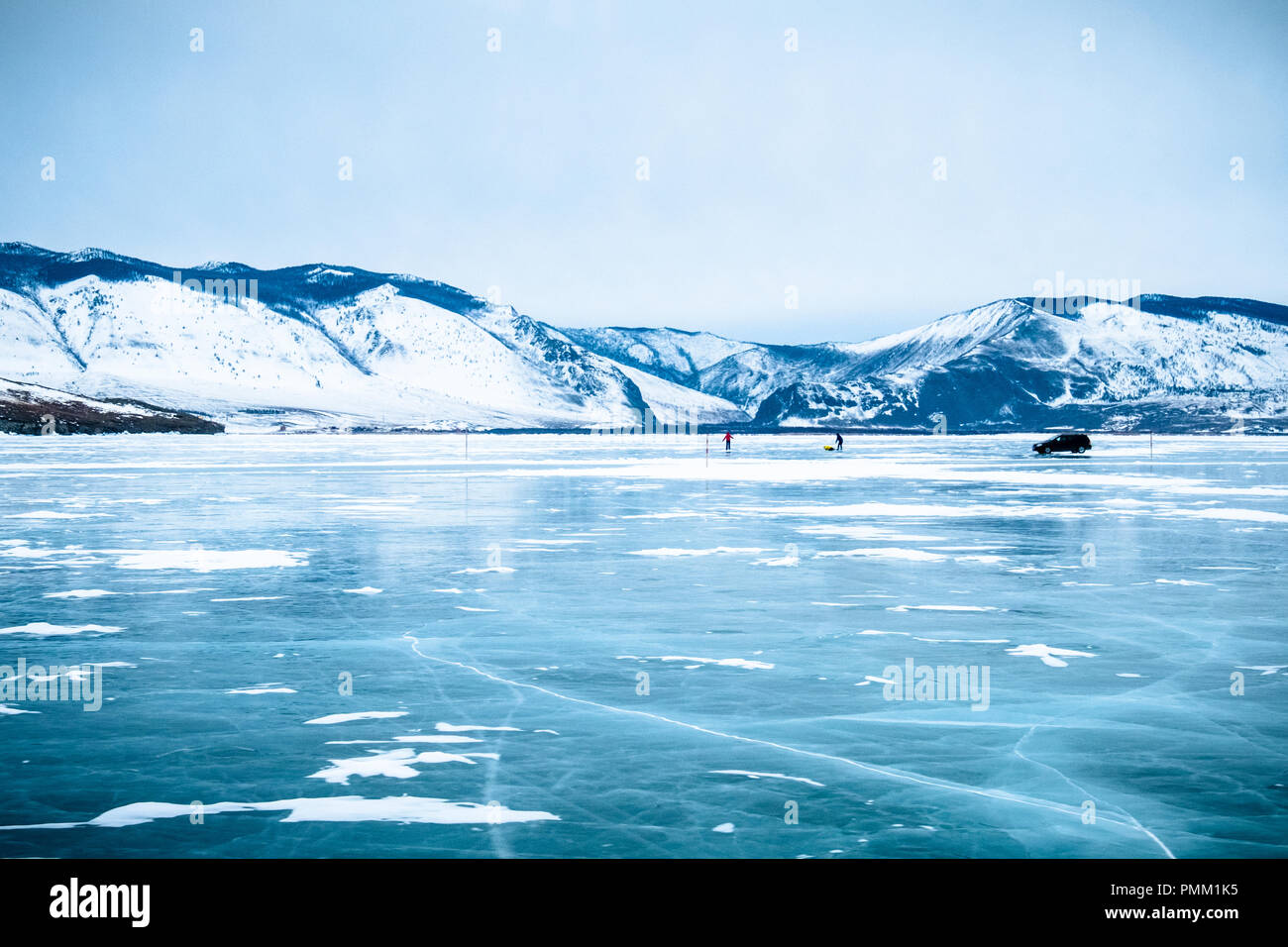 Due persone e un auto su un lago ghiacciato, Siberia, Russia Foto Stock