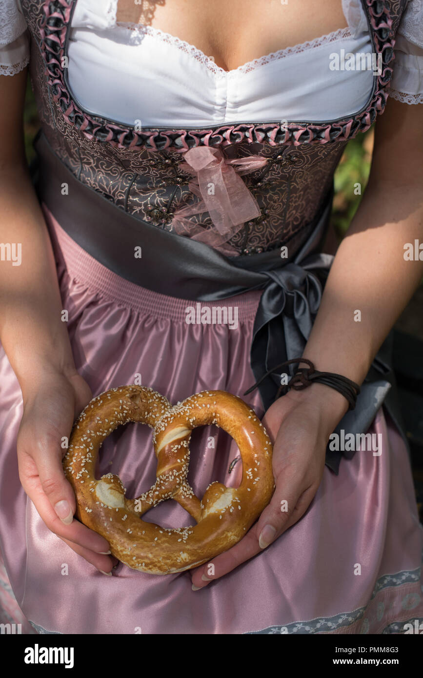 Donna che indossa un tradizionale tedesco dirndl tenendo un pretzel Foto Stock