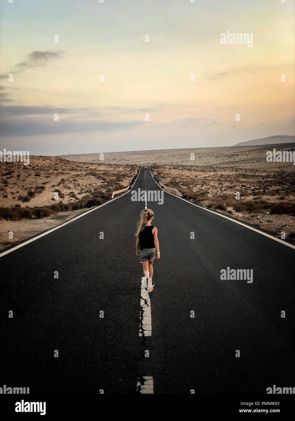 Ragazza camminare giù al centro di una strada, Pajara, Fuerteventura, Isole Canarie, Spagna Foto Stock