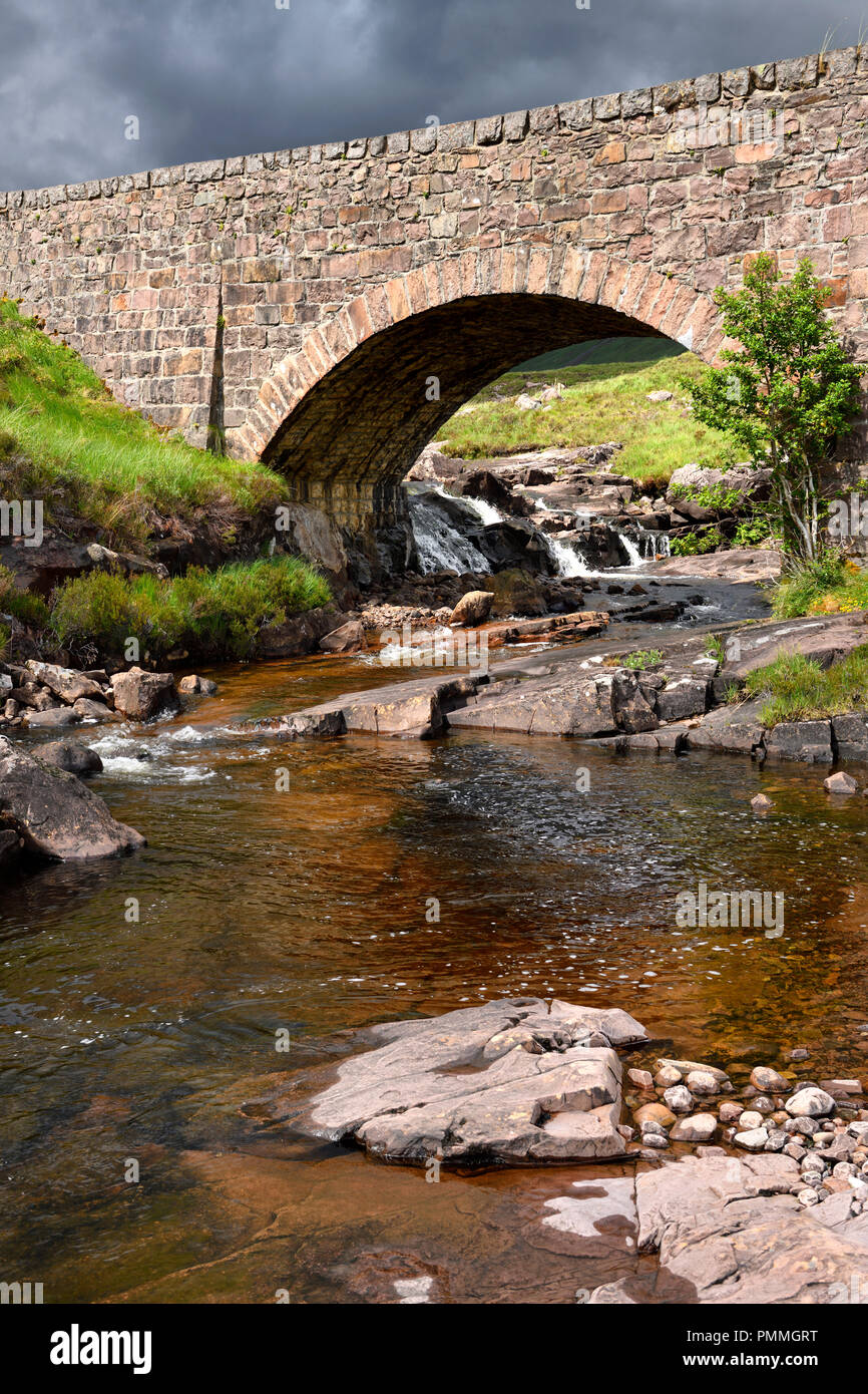 Rosso ponte in pietra di sole sopra Russel Burn River di Bealach na Ba road mountain pass sulla penisola di Applecross Highlands scozzesi Scotland Regno Unito Foto Stock