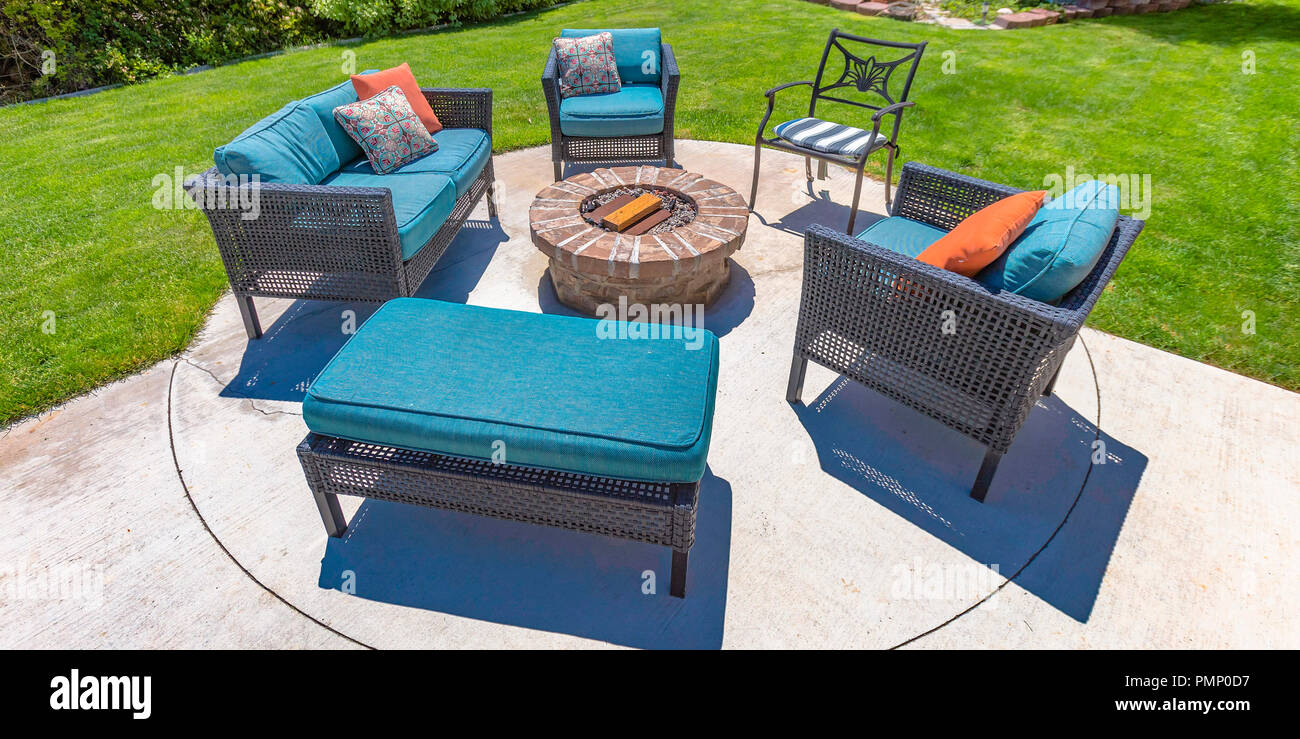 Circolare di una buca per il fuoco e le sedie su un soleggiato cortile Foto Stock