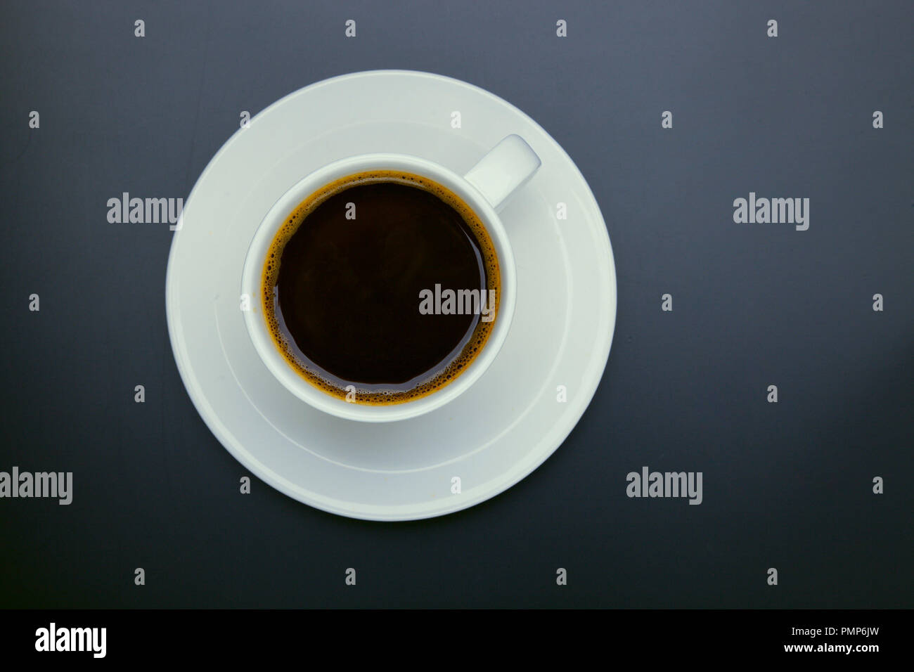Tazza di caffè nero su un tavolo vista piana, laici, mock up. Tazza di caffè nero in ceramica bianca tazza in plastica sul piano portapaziente Foto Stock