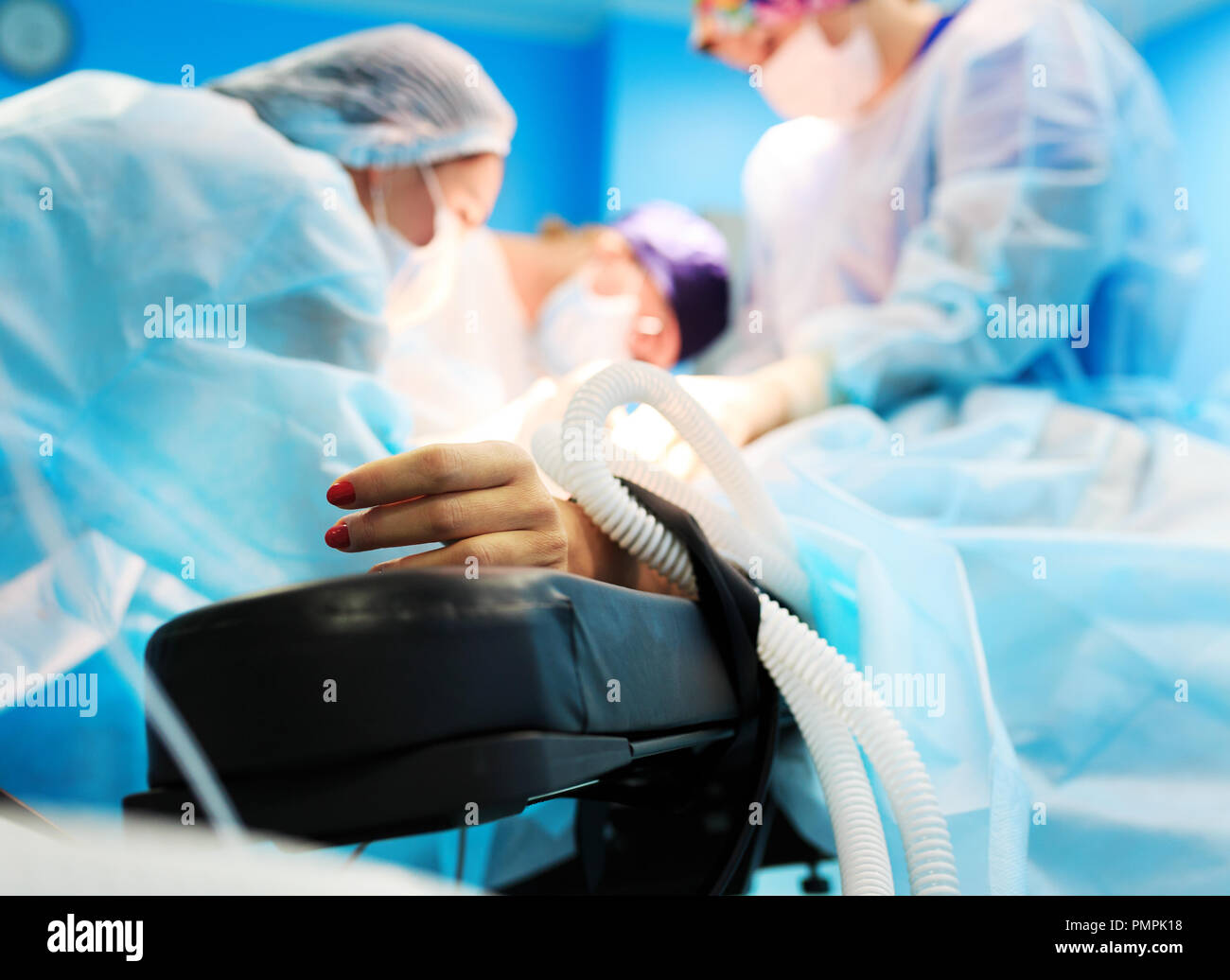 Pazienti con mano un sensore sul sfocata sullo sfondo di un gruppo di medici in sala operatoria. Close up Foto Stock