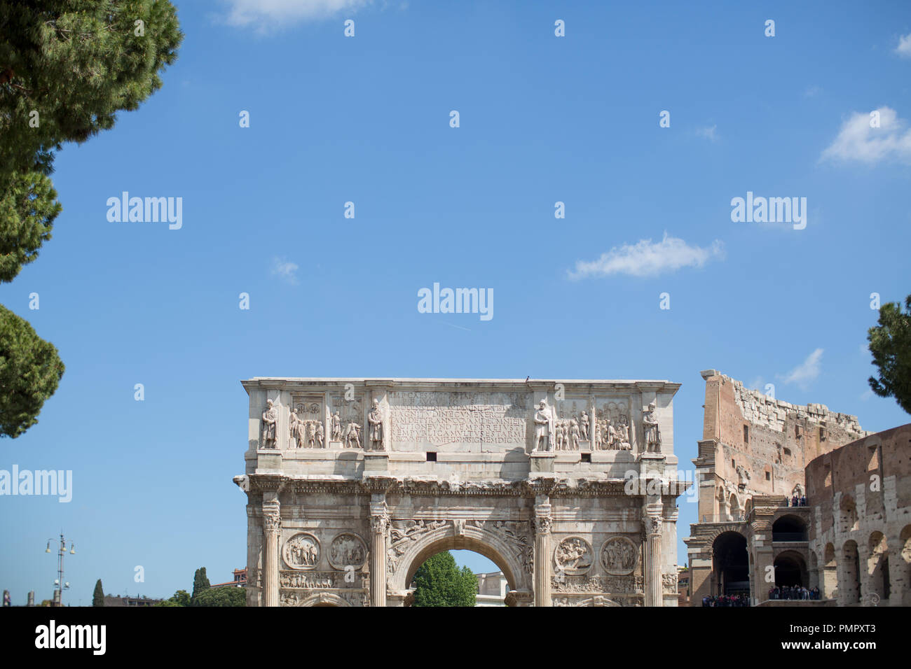 La parte superiore dell'Arco di Costantino a Roma con lo sfondo di un vuoto di Cielo di estate blu e parte del Colosseo di Roma sulla destra Foto Stock