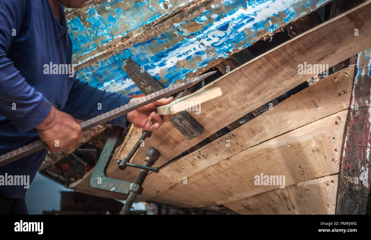 Manutenzione meccanica vecchia barca di legno sulla spiaggia con la mano, la pesca tradizionale baia della Thailandia Foto Stock