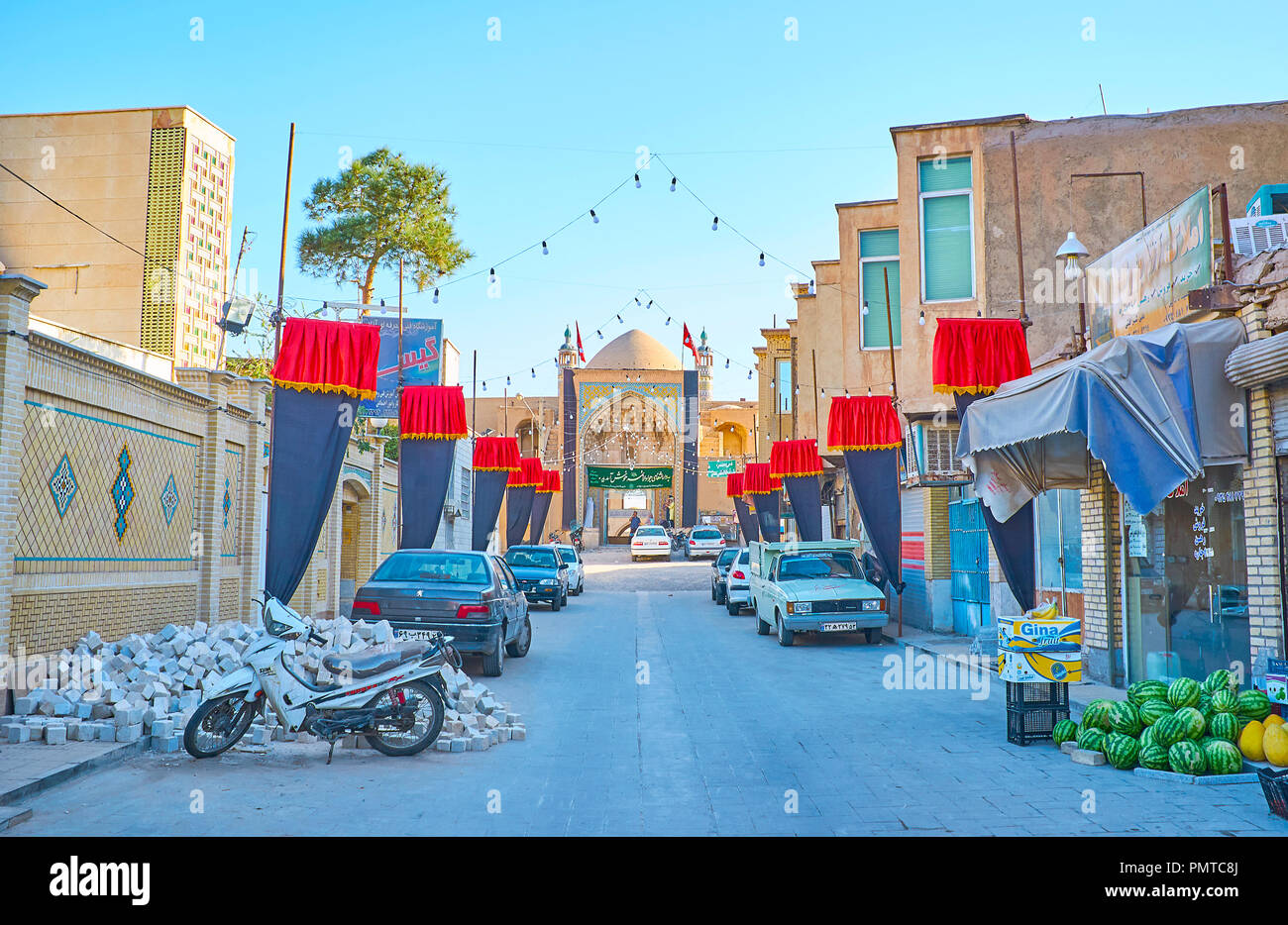 KASHAN, IRAN - 22 ottobre 2017: la strada stretta con le bancarelle del mercato, Muharram bandiere e la iwan (portale) di Agha Bozorg moschea sullo sfondo, o Foto Stock