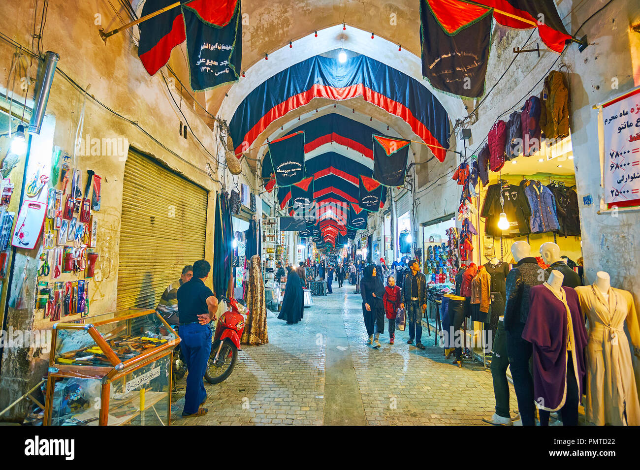 KASHAN, IRAN - 22 ottobre 2017: palazzo medievale del Grand Bazaar con stretto vicoletto pieno di negozi, bancarelle, visitatori e decorate con Muharram Foto Stock