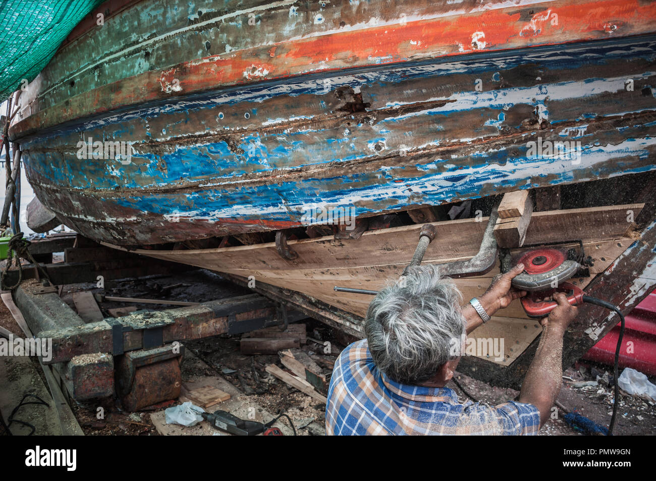 Manutenzione meccanica vecchia barca di legno sulla spiaggia con la mano, la pesca tradizionale baia della Thailandia Foto Stock