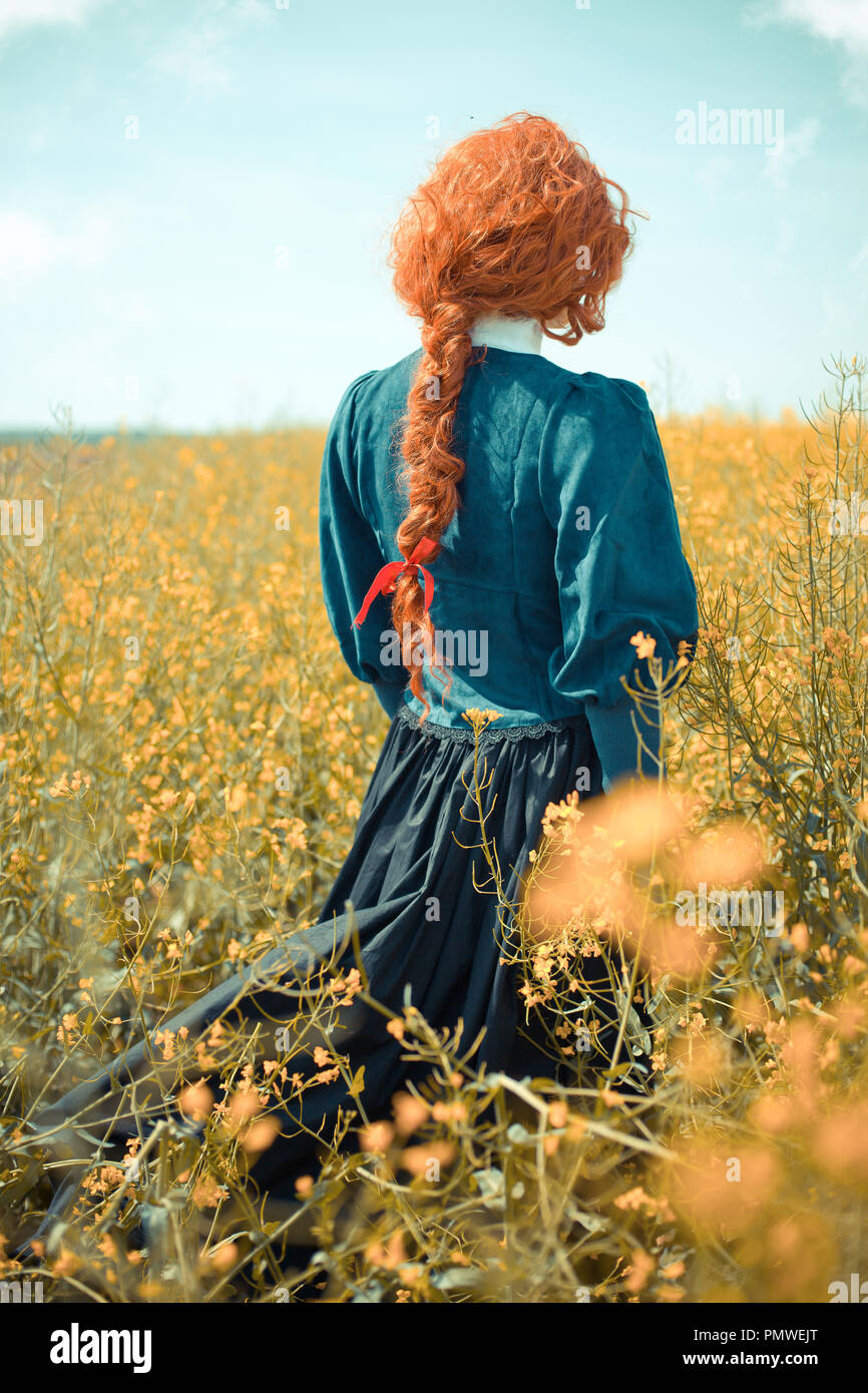 Victorian woman standing nel campo dei fiori in estate Foto Stock