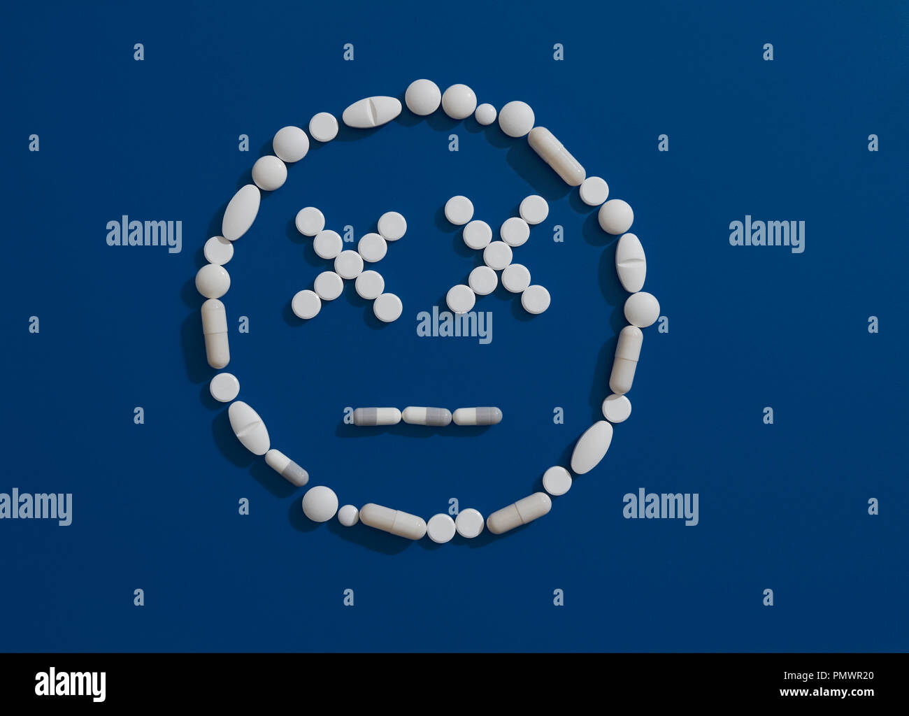 Pills formando dizzy faccia su sfondo blu Foto Stock