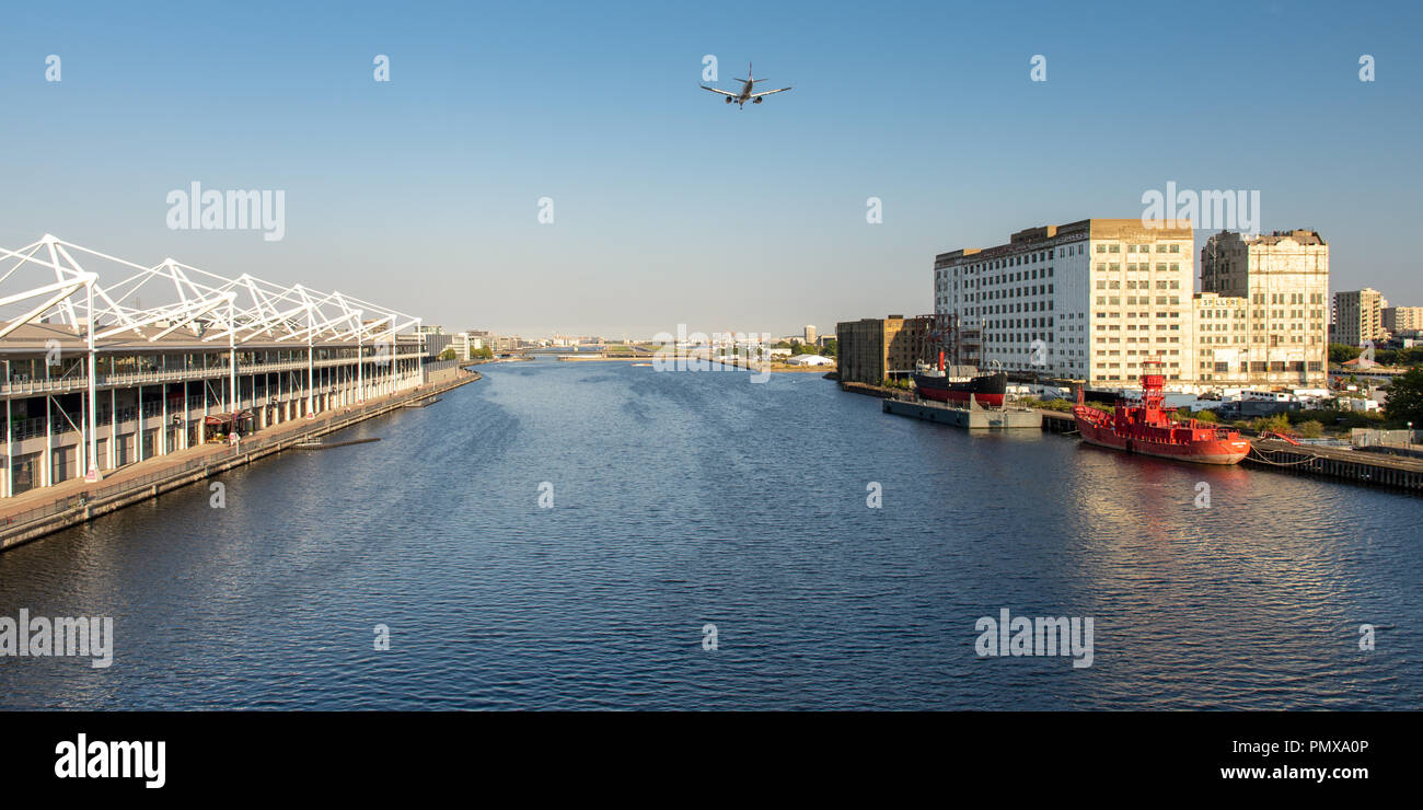 London, England, Regno Unito - 2 Settembre 2018: un piccolo aereo passeggeri vola basso sul Royal Victoria Dock, affiancato dal centro espositivo ExCeL e Mill Foto Stock