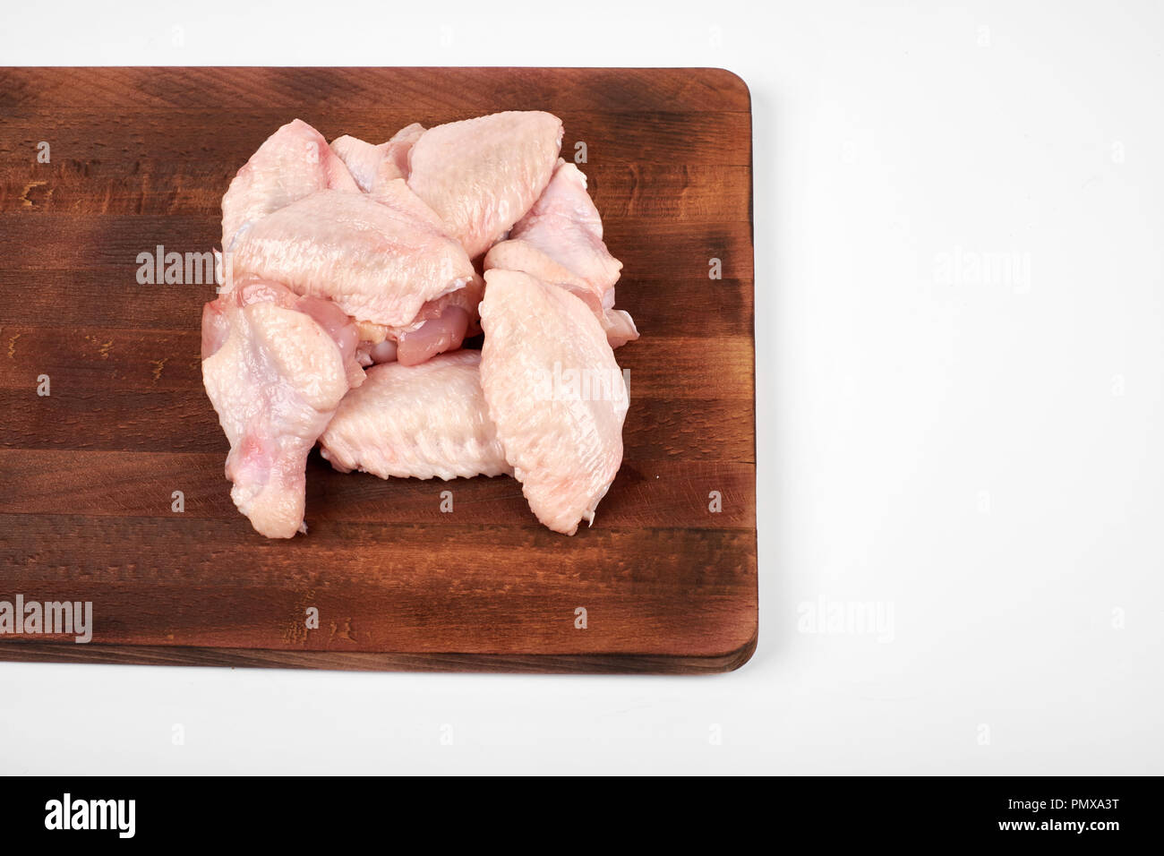 Materie di ali di pollo sul tagliere su sfondo bianco. Foto Stock