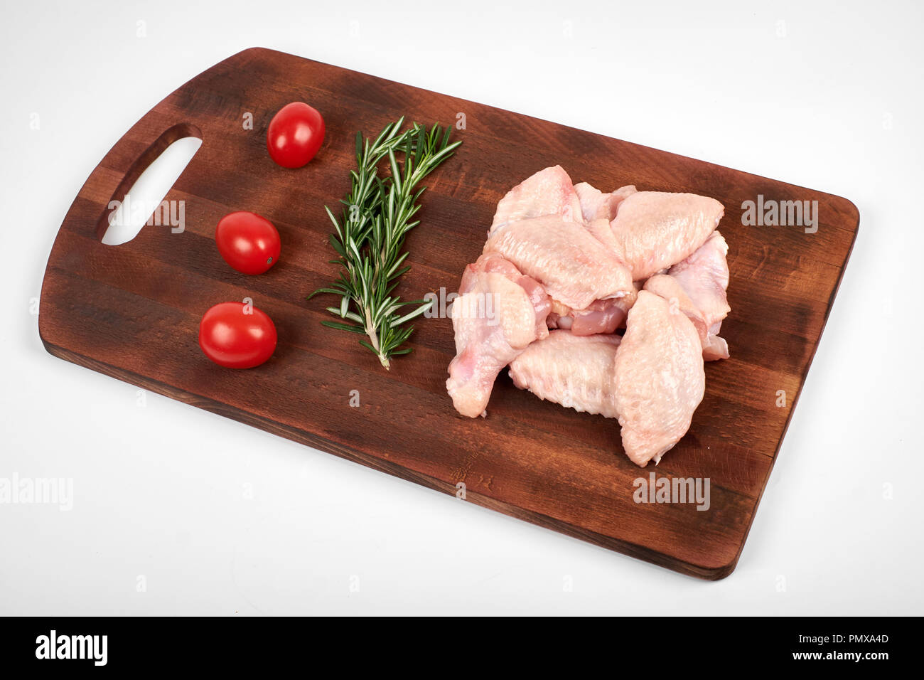 Materie di ali di pollo sul tagliere su sfondo bianco. Foto Stock