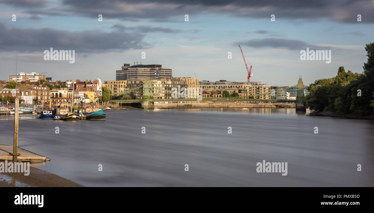 London, England, Regno Unito - 9 Settembre 2018: Serata sole risplende sulla Hammersmith Bridge e il fiume Tamigi riverside, comprese le case tradizionali, moderno Foto Stock