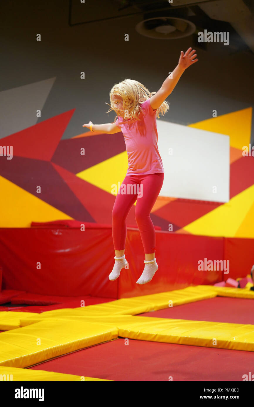 Infanzia felice di un bambino moderno nella città - ragazza il salto nel trampolino park Foto Stock
