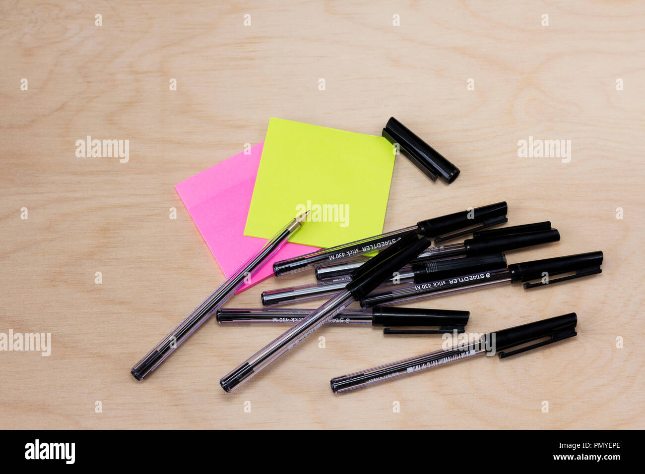 Nero penne biro e colorati alcuni post-it-note su una luce sullo sfondo di legno Foto Stock