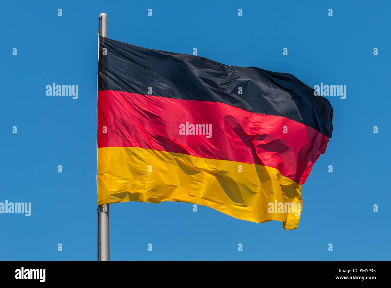 Tedesco bandiere sventolano al vento al famoso palazzo del Reichstag, sede del Parlamento tedesco (Deutscher Bundestag), in una giornata di sole con cielo blu, centr Foto Stock