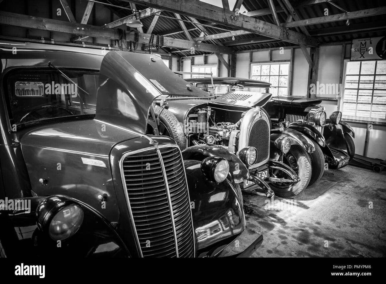 Dettagliato, arty, bianco e nero, paesaggio close up di lucido, lucidati vintage classic cars parcheggiato, affiancate in un garage aperto lo spazio. Foto Stock