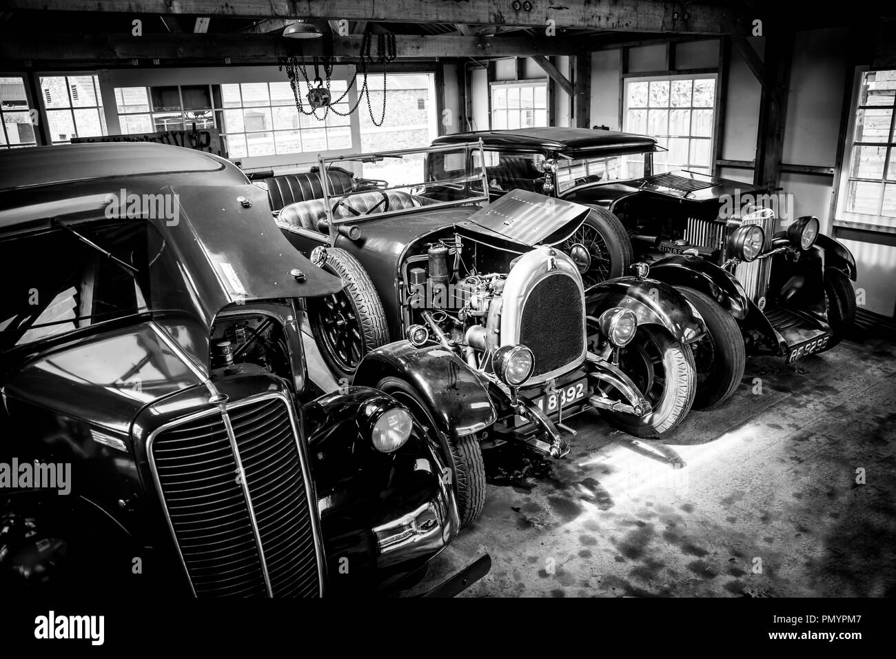 Vista arty, in bianco e nero di auto classiche d'epoca parcheggiate, fianco a fianco, in esposizione in un garage aperto, preso da un'angolazione elevata. Foto Stock