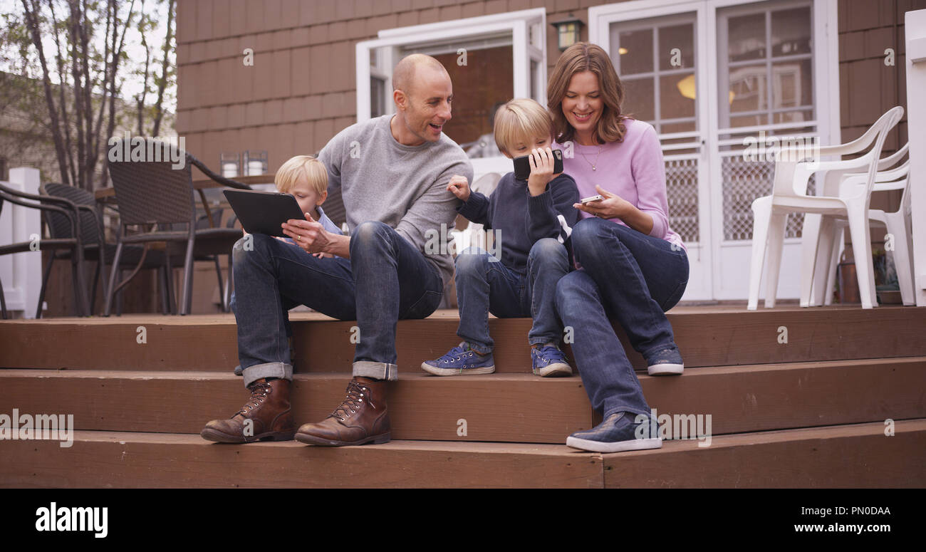 Bella famiglia guardando i dispositivi palmari all'esterno. Foto Stock