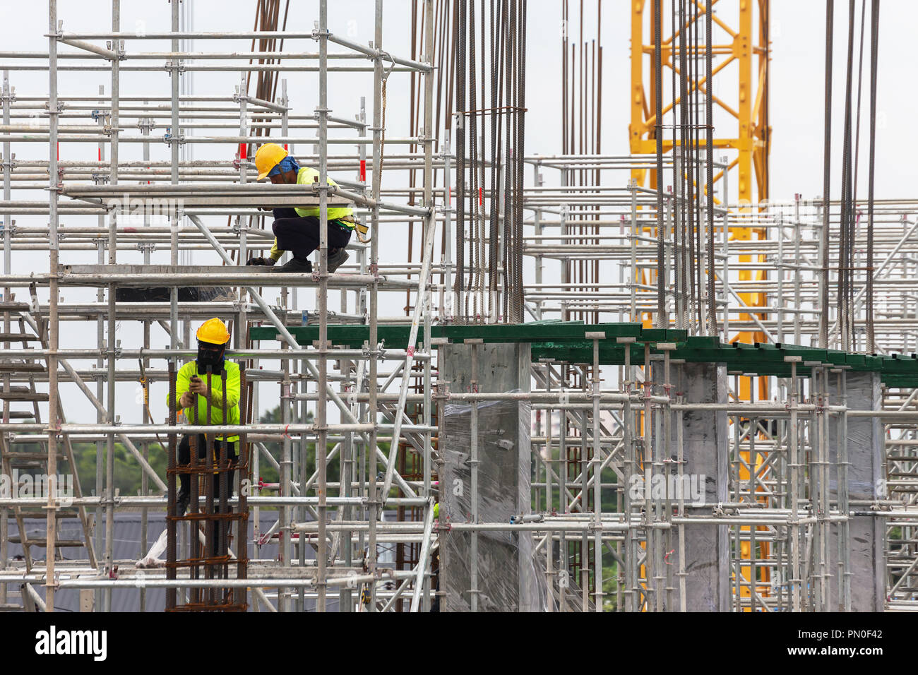 Costruzione asiatica dei lavoratori sui ponteggi di edificio sito in costruzione nella città. espansione urbana nella città capitale di asia sono in rapida crescita Foto Stock