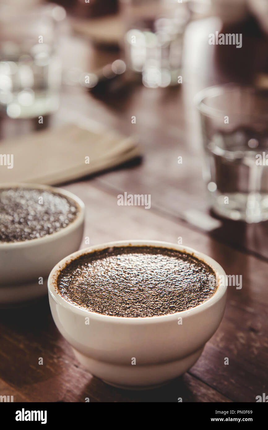 Il caffè macinato con acqua calda nella tazza di ceramica sul tavolo sta preparando per professional Q classificatore per test e ispezione della qualità del caffè. Foto Stock
