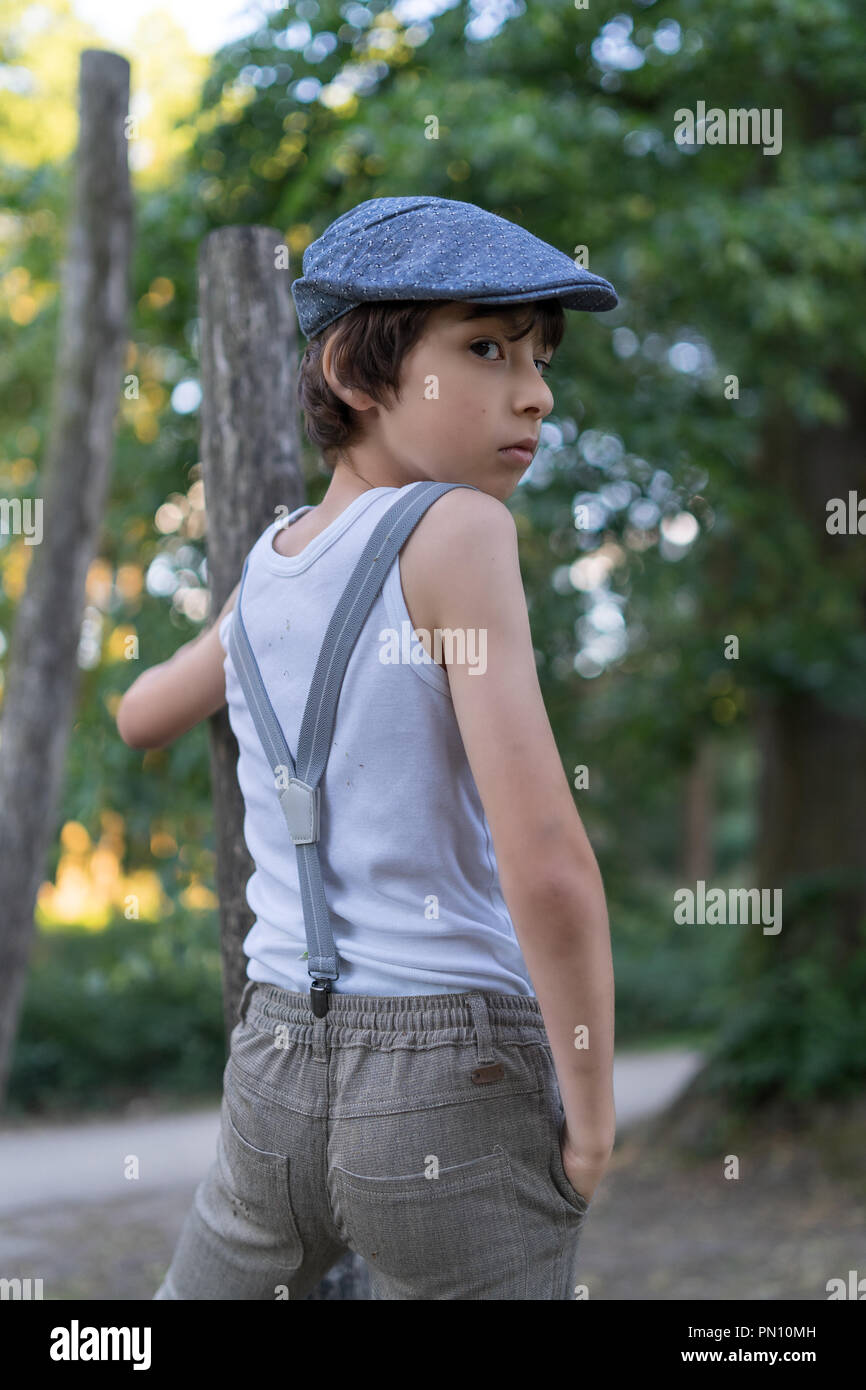 Ritratto di un ragazzo vestito in pantaloni con bretelle e una camicia  senza maniche, contro uno sfondo di natura Foto stock - Alamy