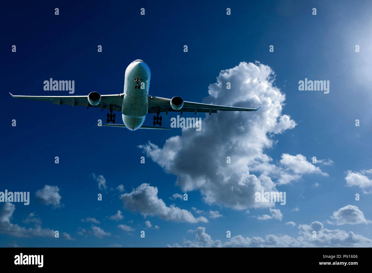 Un artistico skyscape vista di un commerciali di passeggeri aerei jet in volo in una vibrante blu cielo, con luminose colorate di bianco ondeggianti Cumulonimbus nuvole Foto Stock