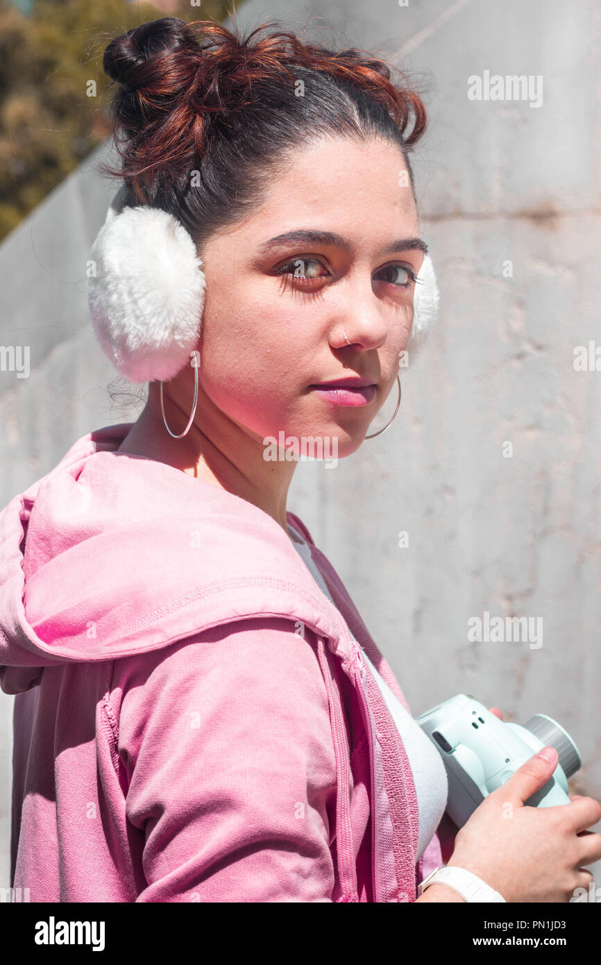 Bruna giovane donna con capelli due panini e bianco cuffie e camicia rosa Foto Stock