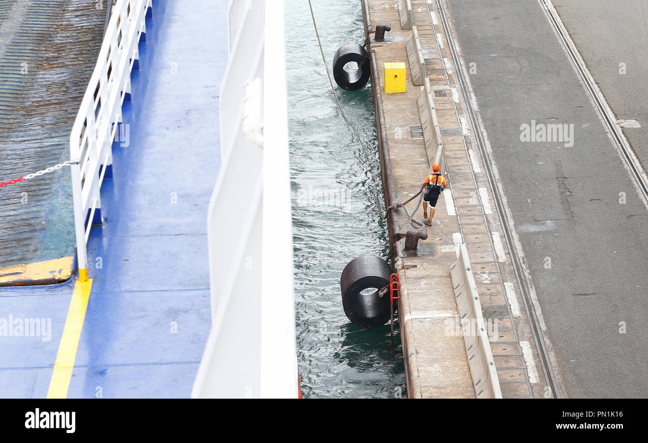 Scaricatore di porto o impresa di movimentazione cammina accanto a una appena arrivati nave nel porto di Barcellona. Foto Stock