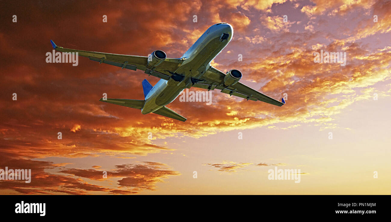 Un passeggero aereo jet volare al di sopra di primo piano con un arancio & Oro Altocumulus colorato la formazione di nubi in un giallo tramonto Cielo. Bellezza atmosferica Foto Stock