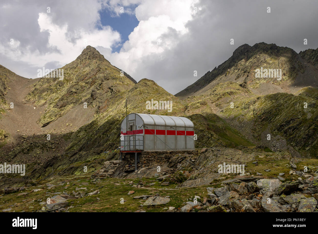 Un piccolo rifugio di acciaio si siede di fronte a due cime. Foto Stock