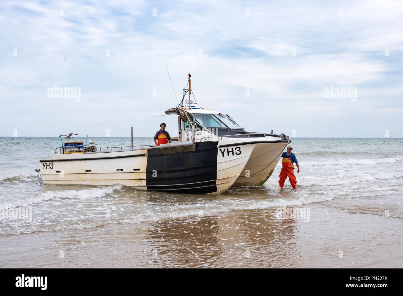 Fisherman sbarcano nella loro barca sulla spiaggia a Cromer, Norfolk, Regno Unito Foto Stock