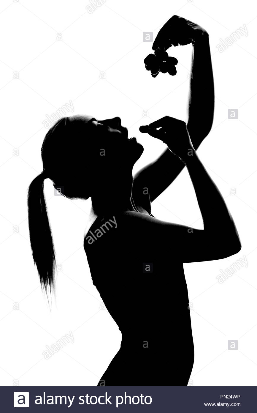 Donna con la coda di cavallo di mangiare da un grappolo di uva Foto Stock