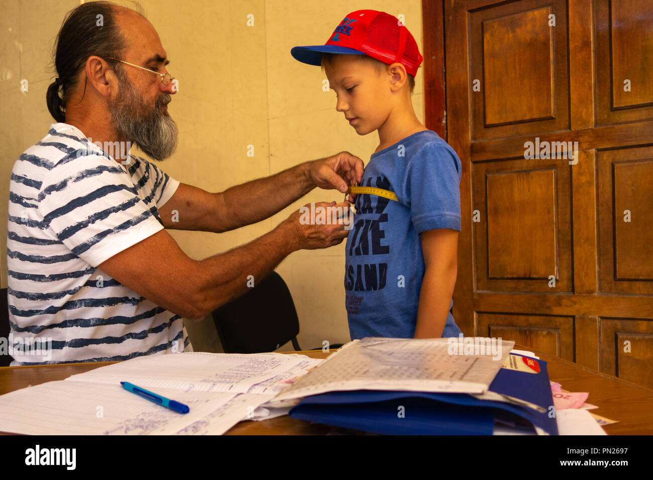 2018.08.08 Odessa. L'Ucraina. Il sarto prenda le misure dal ragazzo per la cucitura di un'uniforme scolastica Foto Stock