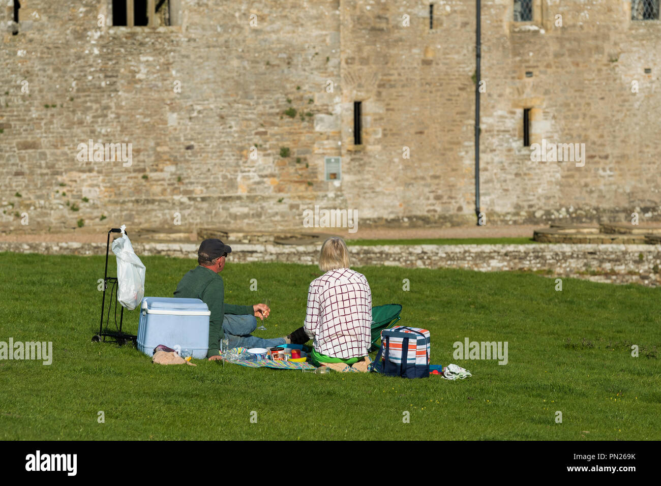 Persone sit & hanno picnic sotto il cielo blu da storico castello medievale nella splendida campagna - Bolton Castle, Wensleydale, North Yorkshire, Inghilterra, Regno Unito Foto Stock