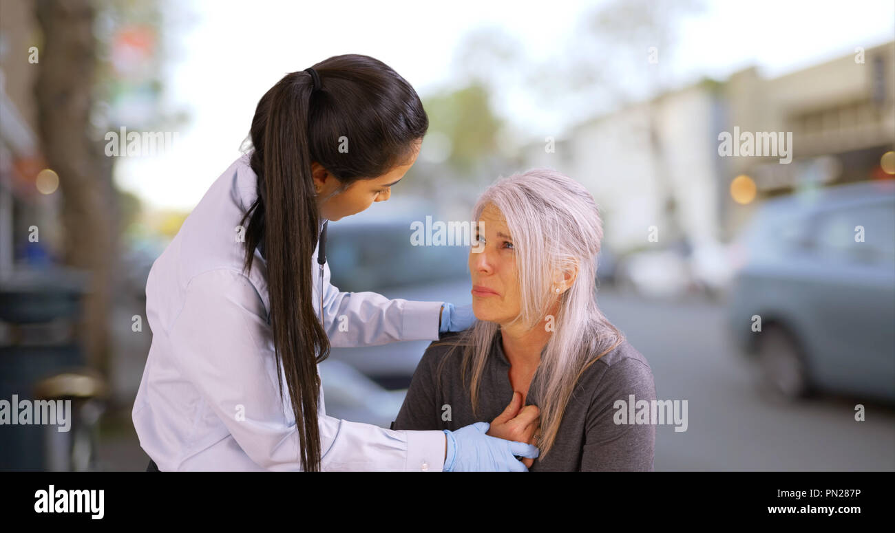 Una donna anziana ha un attacco di cuore sul marciapiede Foto Stock